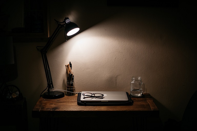 Laptop and glasses on desk in the dark